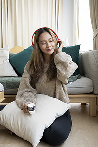 在客厅里喝咖啡 听着耳机音乐的年轻女性也放松了下来图片