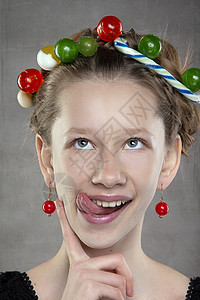 一个带着甜食花圈的有趣的少女 头部露出她的舌头图片
