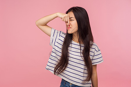 粉红色背景的亚洲年轻女性肖像条纹香气呼吸女孩黑发情感斥力鼻子女士厌恶图片