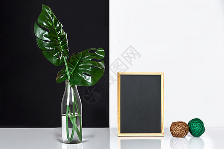 时尚的内衣装饰了海报框 玻璃瓶里的叶子放在桌子上 背景上有黑白墙小样玻璃客厅木头盒子作品房间架子照片框架图片
