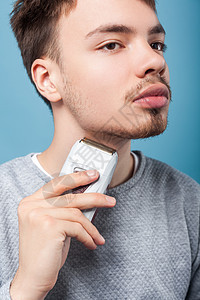 蓝色背景的年轻男子的美容和保健护理男性修剪脸颊机器胡子头发理发师卫生身体图片