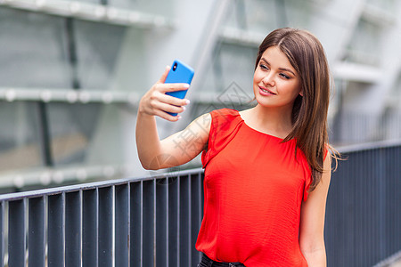 年轻妇女在户外走动 使用移动电话享受手机学生博客衬衫电话照片摄影互联网黑发图片