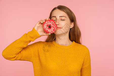 粉红色背景的年轻情感女性的肖像诱惑面包欲望饮食毛衣女孩早餐营养甜点女士图片