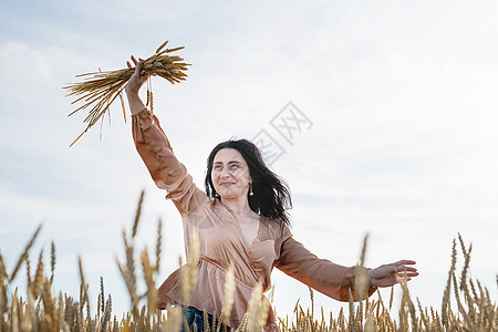 身穿米色衬衣的中成年妇女站在小麦田上 背景 背面和背面有日出女性幸福头发快乐天空草地植物农业裙子大麦图片