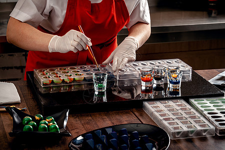 一位穿红色制服和白手套的美食者 用乳巧克力特制的糖果 配有可食用涂料艺术动物木头喜悦巧克力甜点咖啡哺乳动物工作室蓝色图片