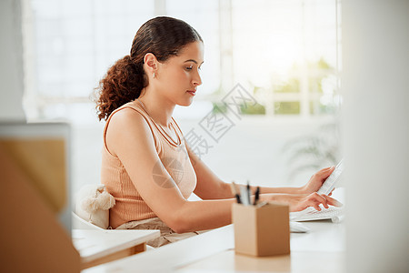 一位年轻的西班牙裔女商务人士在办公室的电脑上工作时使用计算器 专注于计算税收 网上银行和预算支出财务的企业家图片