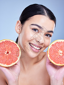 一个快乐的混血女人拿着葡萄柚的画像 在蓝色复制空间背景下推广柑橘对皮肤有益的西班牙裔模特图片