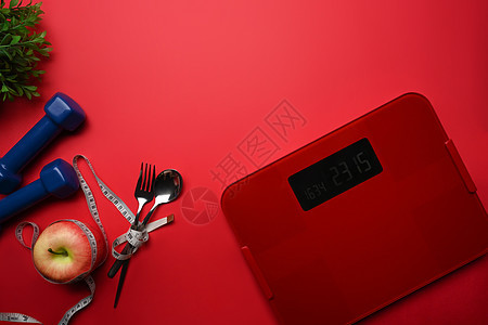 体重比重与测量胶带 苹果和哑铃 在红色背景图片