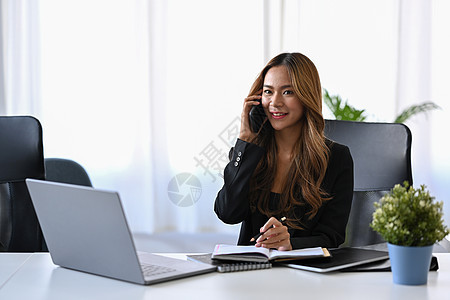 美丽的女商务人士坐在明亮的现代办公室里 在移动电话上交谈图片
