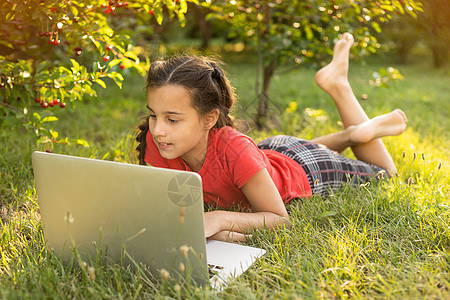 美丽的小姐姐在户外和朋友聊天 置身于大自然中很有用 笔记本电脑是当今孩子最好的朋友 绿色广阔的草地互联网技术微笑花园季节教育太阳图片