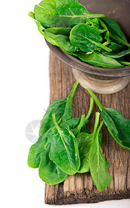 白色背景的木板上的新鲜绿色 健康菠菜树叶盘子图片