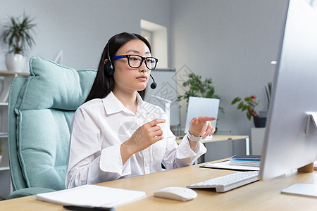 远程工作的顾问女性使用耳机进行视频通话 与客户交谈 求助热线 在办公室工作的亚洲女性图片