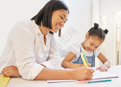 混血母亲帮助女儿做家庭作业 妈妈在家教课上教女儿读书写字 小女孩和家教坐在家里图片