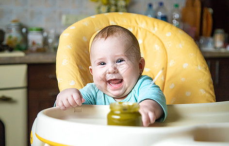 小宝宝在吃花椰菜 有选择的专注点椅子母亲孩子们勺子微笑饮食香蕉桌子孩子食谱图片