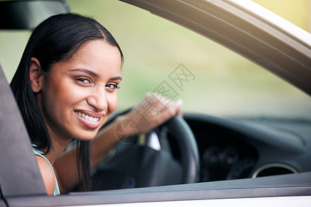 性格开朗的混血女人开着她的新车 微笑的年轻女子坐在驾驶座上看着她的车窗外 然后去兜风 考驾照或试驾 汽车保险图片