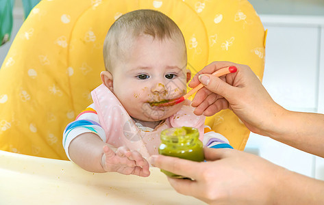 小宝宝在吃花椰菜 有选择的专注点午餐营养快乐孩子母亲勺子水果微笑饮食家庭图片