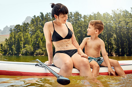 他喜欢待在水里 拍到一个有魅力的年轻女人和她儿子在湖边玩得开心的照片图片
