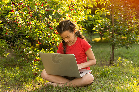 美丽的小姐姐在户外和朋友聊天 置身于大自然中很有用 笔记本电脑是当今孩子最好的朋友 绿色广阔的草地女孩季节学校童年花园卡通片教育图片