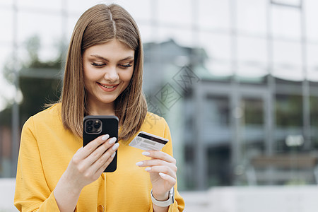 女手在智能手机中键入银行卡号 使用数字移动设备持有信用卡并在网上购物的白人女性图片