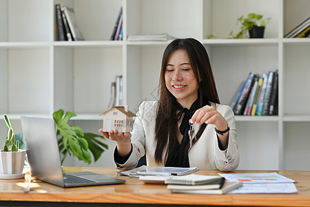 房地产经纪人持有小房子模型和钥匙 房地产投资概念 (笑声)图片