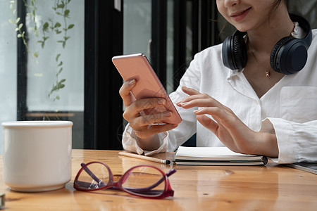 近距离接近一位年轻的亚洲女性使用移动智能手机在家上线学习时商务女孩女士微笑男人男性屏幕青少年办公室技术图片