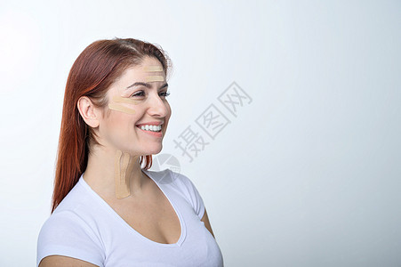 一个红发女人的肖像 带着彩色脸部的磁带 以恢复活力 另一种方法来对抗皱纹青年石膏贴花治疗美容美容师化妆品灵活性化妆师眼皮图片