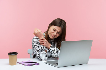 有情感的年轻女性 坐在办公室工作 有粉红色背景商业手臂身体腕管职场手腕疾病伤害创伤黑发图片