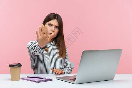 有情感的年轻女性 坐在办公室工作 有粉红色背景黑发电脑禁令安全骚扰女士危险手势警告侮辱图片