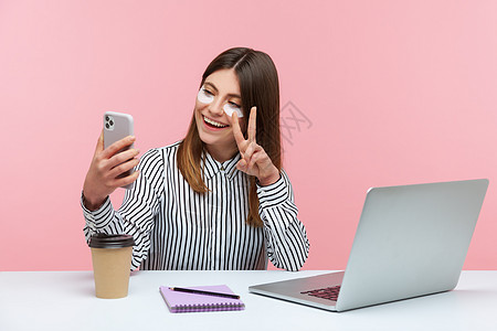 玉石拍摄图片有情感的年轻女性 坐在办公室工作 有粉红色背景博主记录视频电话博客女士美容笔记本工具商业背景