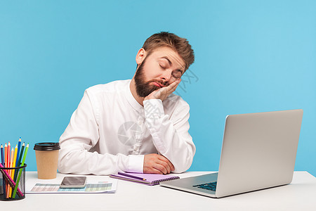 情感商务人士在蓝背景的笔记本电脑上工作工人倾斜商业人士男性活力压力男人疲劳成人图片