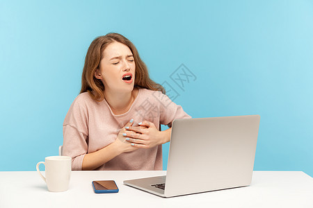 情感年轻女性在蓝背景的笔记本电脑上工作中风女士痛苦疾病商业药品肋骨梗塞疼痛卫生图片