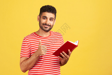 穿着红色T恤穿黄色背景的情绪年轻男子教科书阅读图书馆诗歌小说阴谋笔记本成人沉思胡子图片