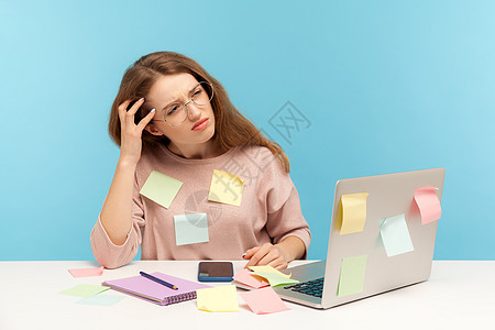 情感年轻女性在蓝背景的笔记本电脑上工作员工办公室沉思文书女士思维思考学生贴纸职场图片