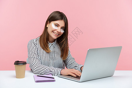 有情感的年轻女性 坐在办公室工作 有粉红色背景笔记本女士乐趣黑发电脑咖啡动机美丽快乐活力图片