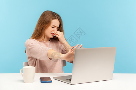 情感年轻女性在蓝背景的笔记本电脑上工作手指自由职业者人士屏幕厌恶呼吸耻辱气体商务互联网图片