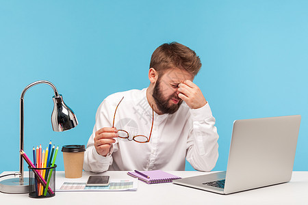 情感商务人士在蓝背景的笔记本电脑上工作痛苦胡子感染成人压力蓝色人士卫生男性疼痛图片