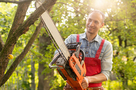 一个男人用电锯锯树工作服链锯汽油森林工具胡须机器野营力量工人图片