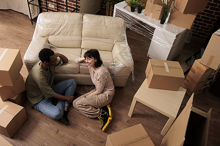 中国风客厅不同已婚夫妇坐在公寓楼层并享受搬迁的舒适生活;背景