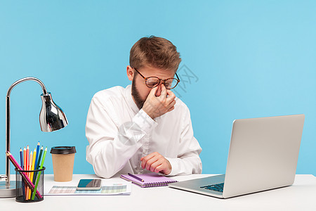 情感商务人士在蓝背景的笔记本电脑上工作眉头卫生男人商务痛苦疾病商业蓝色胡子保健图片