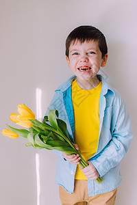 一个男孩带着一束郁金香的生活方式 3 月 8 日的明信片 祝贺妇女节 祝贺母亲节 花是郁金香喜悦展示礼物妈妈微笑孩子们母亲快乐惊图片