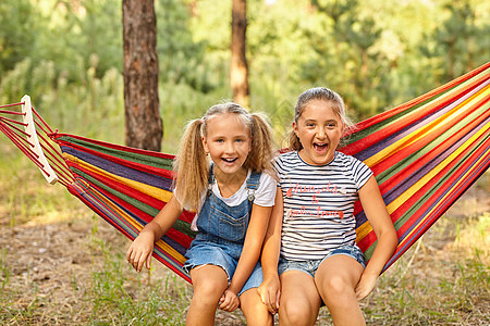 孩子们在多彩彩虹吊床里放松 孩子在放松休息朋友们闲暇后院女孩们公园情感喜悦童年假期图片