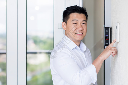 亚洲商务人士肖像 男人走进现代办公室 用门铃和指纹来敲门铃图片