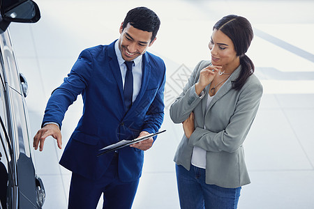 一位英俊的年轻男汽车推销员 在展厅地板上跟女顾客说话 他把车停在了楼层图片