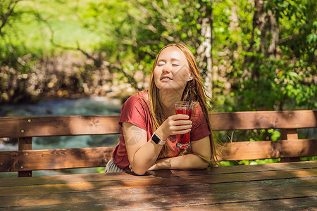 女人在夏天喝健康的水果和蔬菜汁冰沙 享用有机饮料的愉快的女孩闲暇女士假期桌子咖啡店快乐糖果稻草果汁玻璃图片