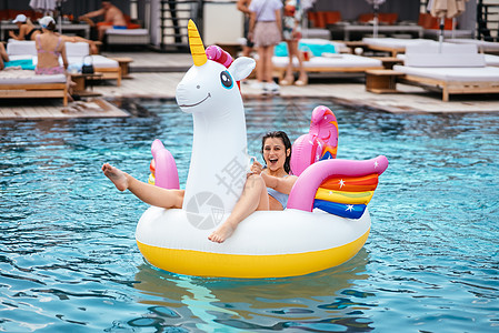 女人在泳池里用可充气的独角兽玩具床垫漂浮旅游火烈鸟假期天堂旅行粉色女士泳装水池比基尼图片