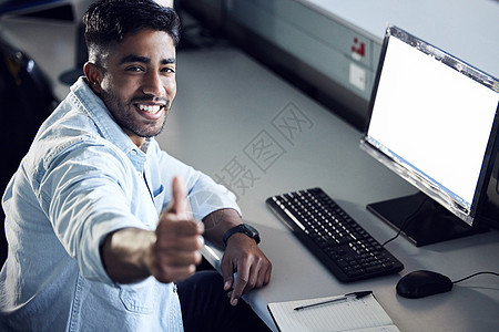 一个年轻人在大学里举起拇指 并使用电脑的图片