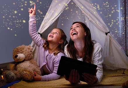 谁说魔法不存在 一个小女孩和她的母亲在睡前使用数字平板电脑图片