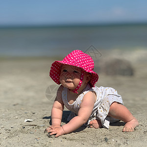 穿着粉色夏帽的女婴在海滩上爬来爬去幸福孩子女儿活动海岸快乐游泳探索太阳旅游图片