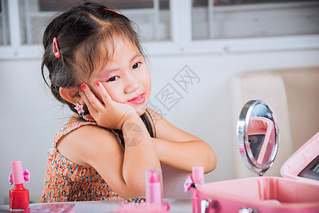 快乐孩子的近身很漂亮 面容装扮成化妆品玩具裙子镜子好奇心女儿女性艺术家抛光女士沙龙刷子图片