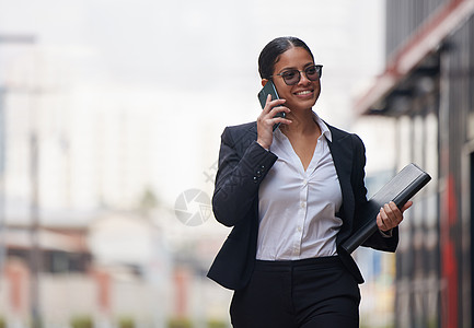 早上第一件事就是完成那些重要的电话 一位迷人的年轻女商务人士在早上通勤时穿过城市并使用她的手机图片